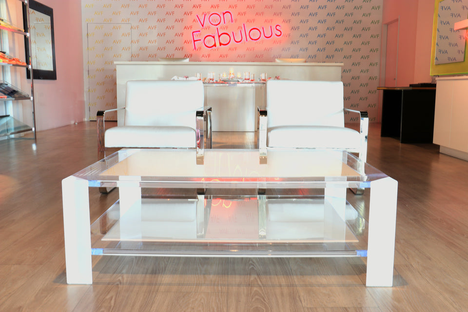 Alexandra Von Furstenberg acrylic lucite clear and white coffee table in a shop with two matching chairs.