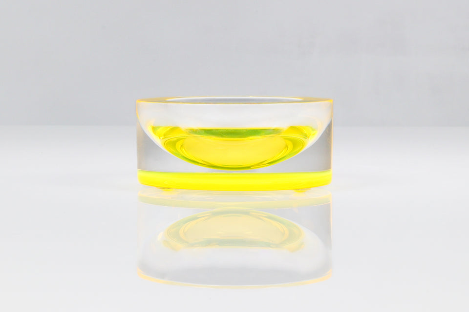 Yellow mini bowl on w white table. Bowl is being viewed head on.