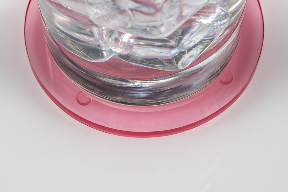 Zoom in of AVF logo on lucite coaster. Water glass is sitting on the tulip coaster. 