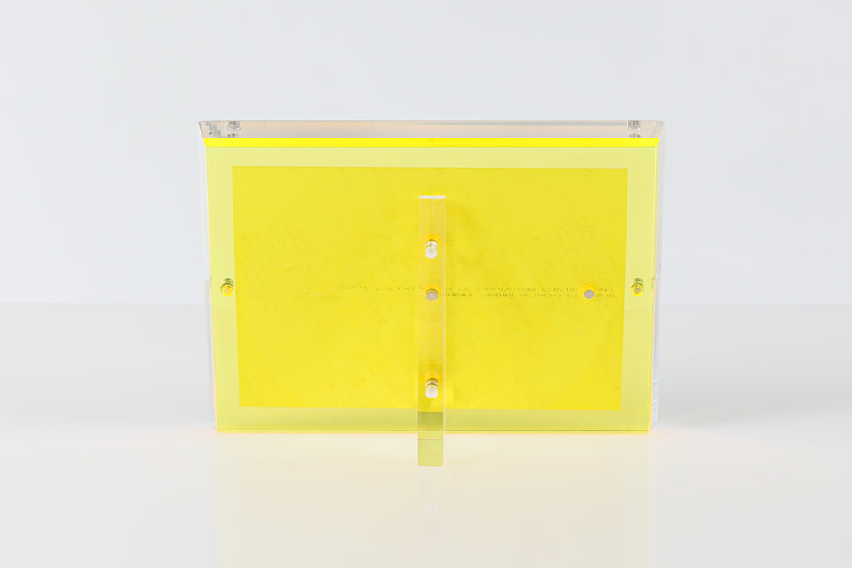 Yellow lucite picture frame. looking at the back of the yellow alexandra von furstenberg frame seeing the magnets in the back and the stand. 
