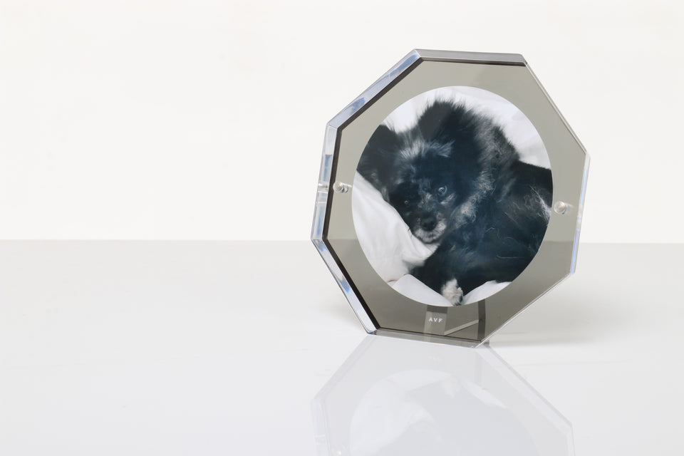 Bolt picture frame in slate grey that fits a 5x5 photo resting on a white table. 