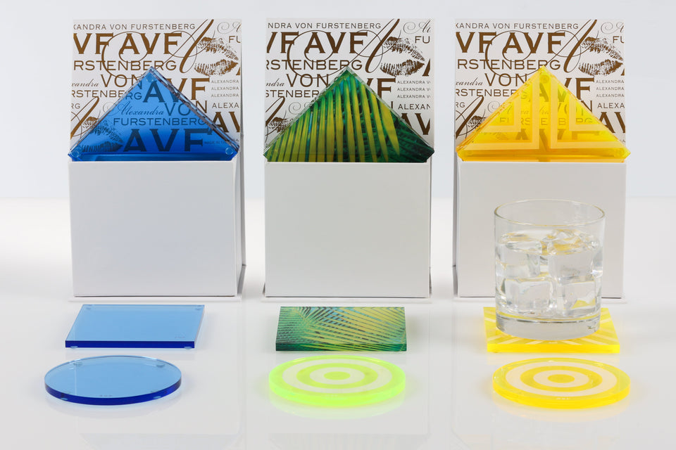 Colorful coasters with Alexandra Von Furstenberg packaging on a white background. Palm, lagoon, and yellow coasters. 