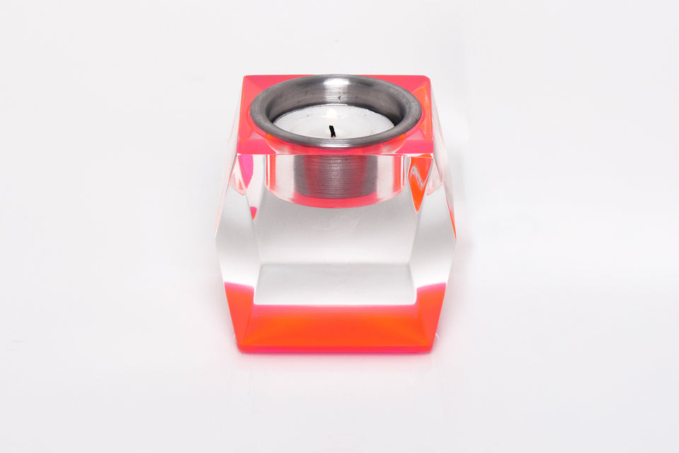 short candleholder in pink. Clear body and a pink base. A candle sits inside the candleholder. 