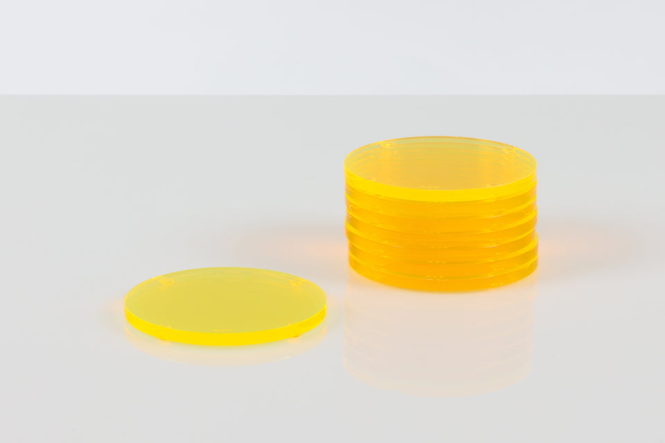 Yellow round coasters, a stack of seven next to a solo coaster set on a white table. 