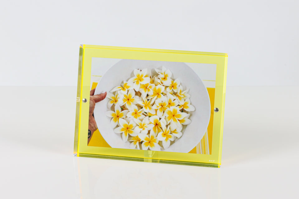 The yellow alexandra von furstenberg picture frame for 5x7 pictures. The yellow frame holds a photo of a dish with some yellow flowers.