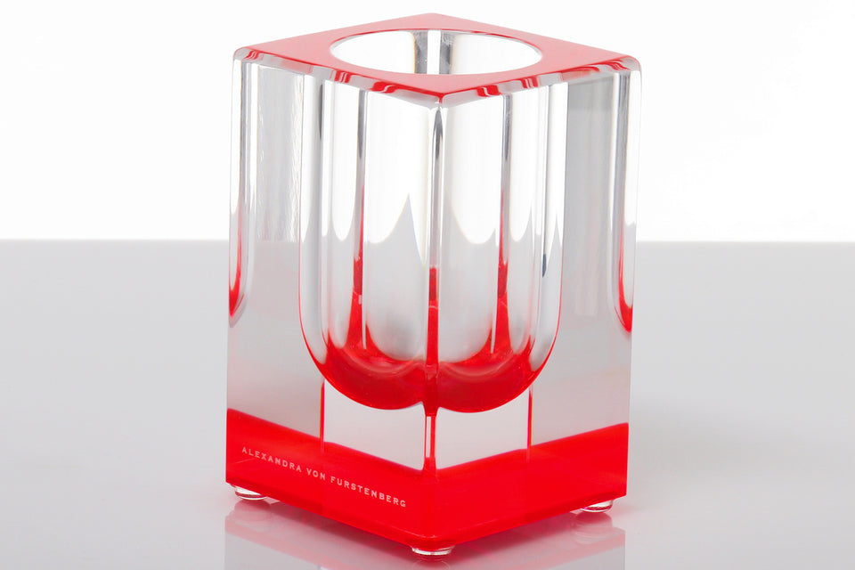 Red acrylic vase. Clear body with red base that gives the vase color. set against a white background. 