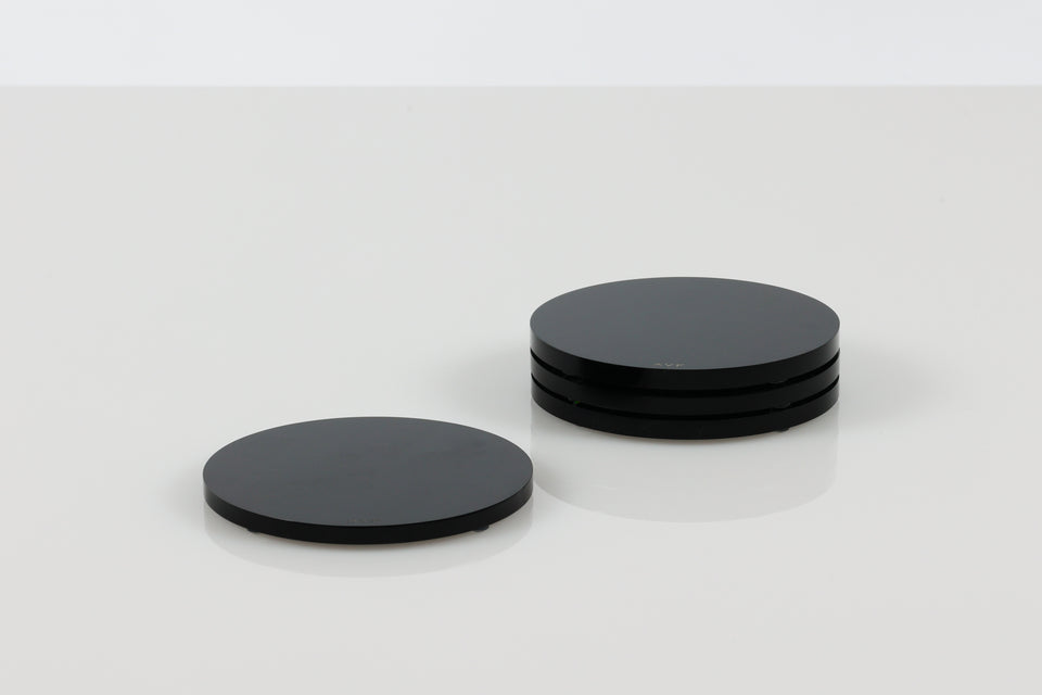 stack of three round lucite black coasters set next to a solo coaster. AVF home coaster on a white background. 