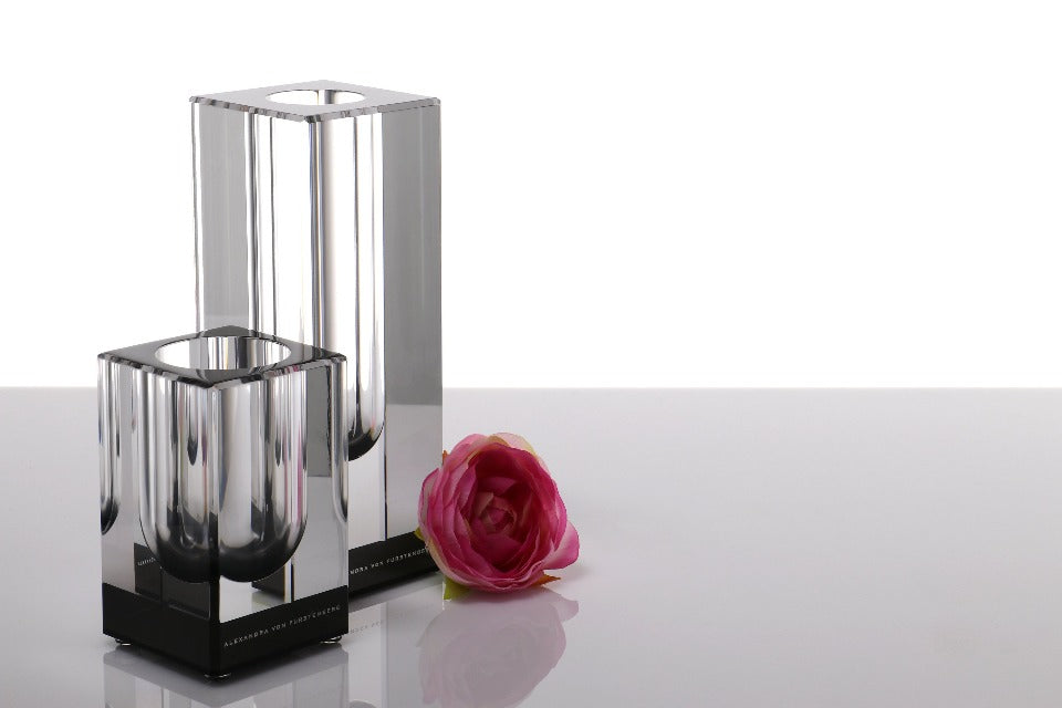 Short and tall cylinder bud vase made of clear acrylic with black accent next to rose