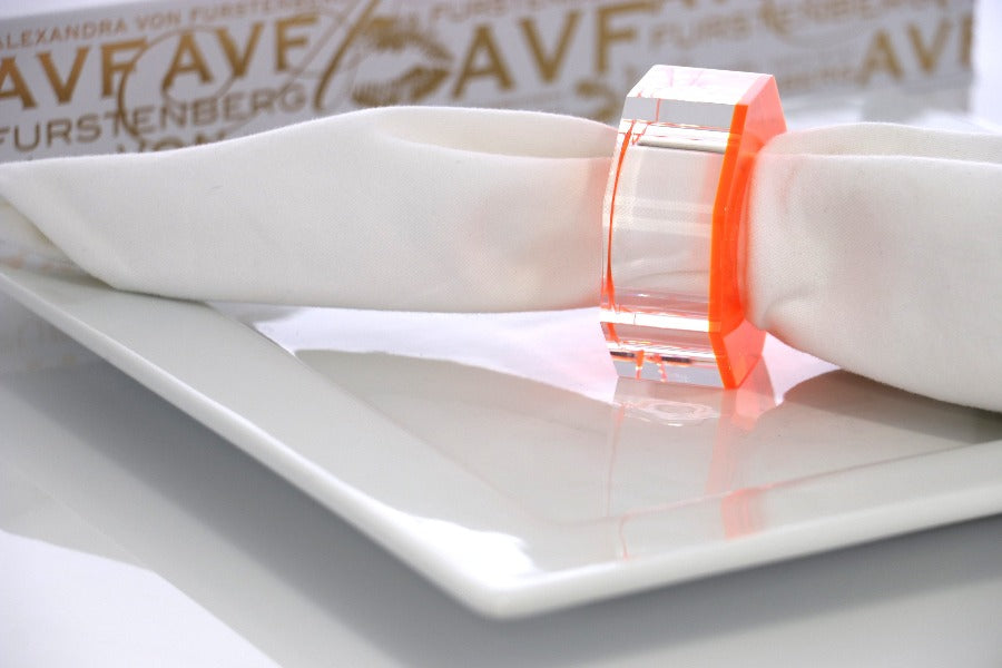 Alexandra Von Furstenberg Acrylic Dinner Napkin Rings in Orange showing 6 rings with a napkin in one. 