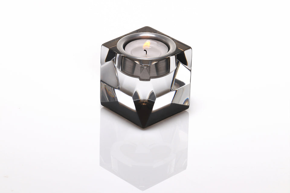 Short votive candle holder with a lit candle. Candleholder has a bronze base with a clear body