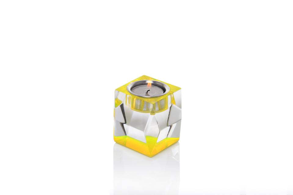 Votive tea light candle holder in yellow with a lit tea light. Short candleholder set on a white background. 