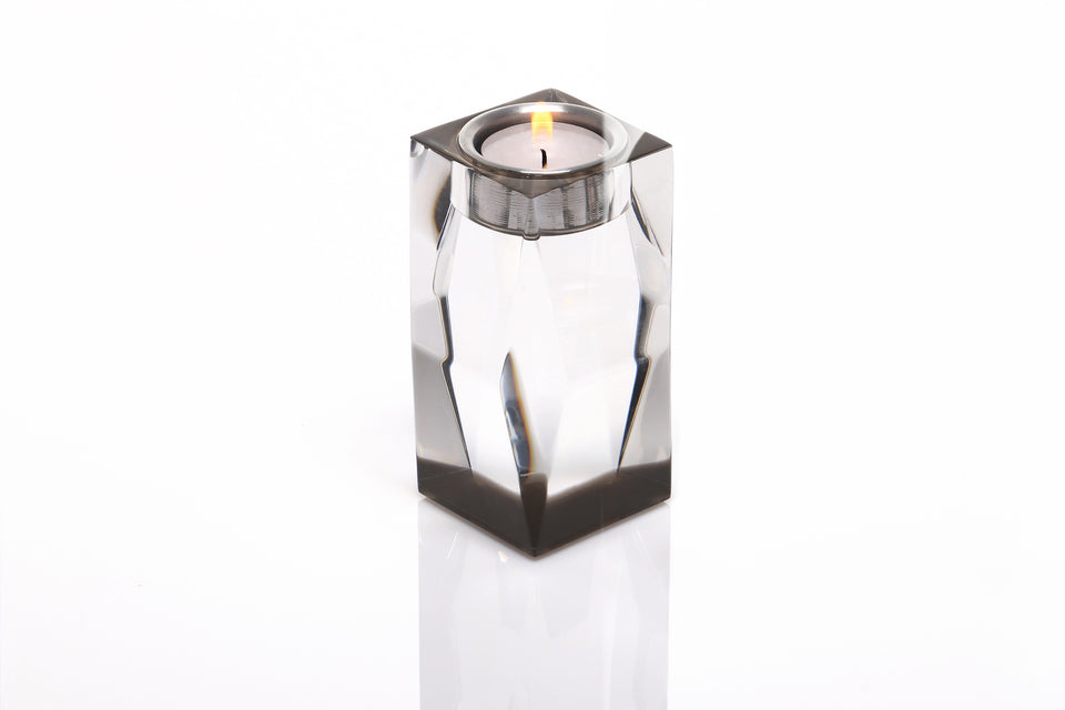 Bronze acrylic sculpted candleholder, which is holding a lit candle. Base of the candleholder is bronze with a clear body. 