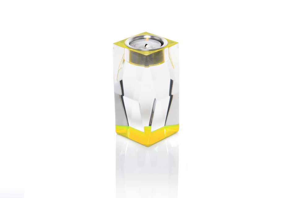 Tall votive tea light candleholder in yellow made from luxury lucite. holding a lit tea light set on a white background. 