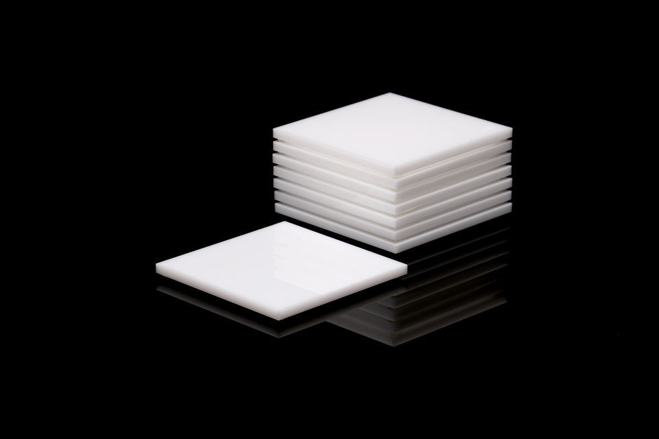 Alexandra Von Furstenberg Acrylic lucite drink coasters in white stacked in a pile.